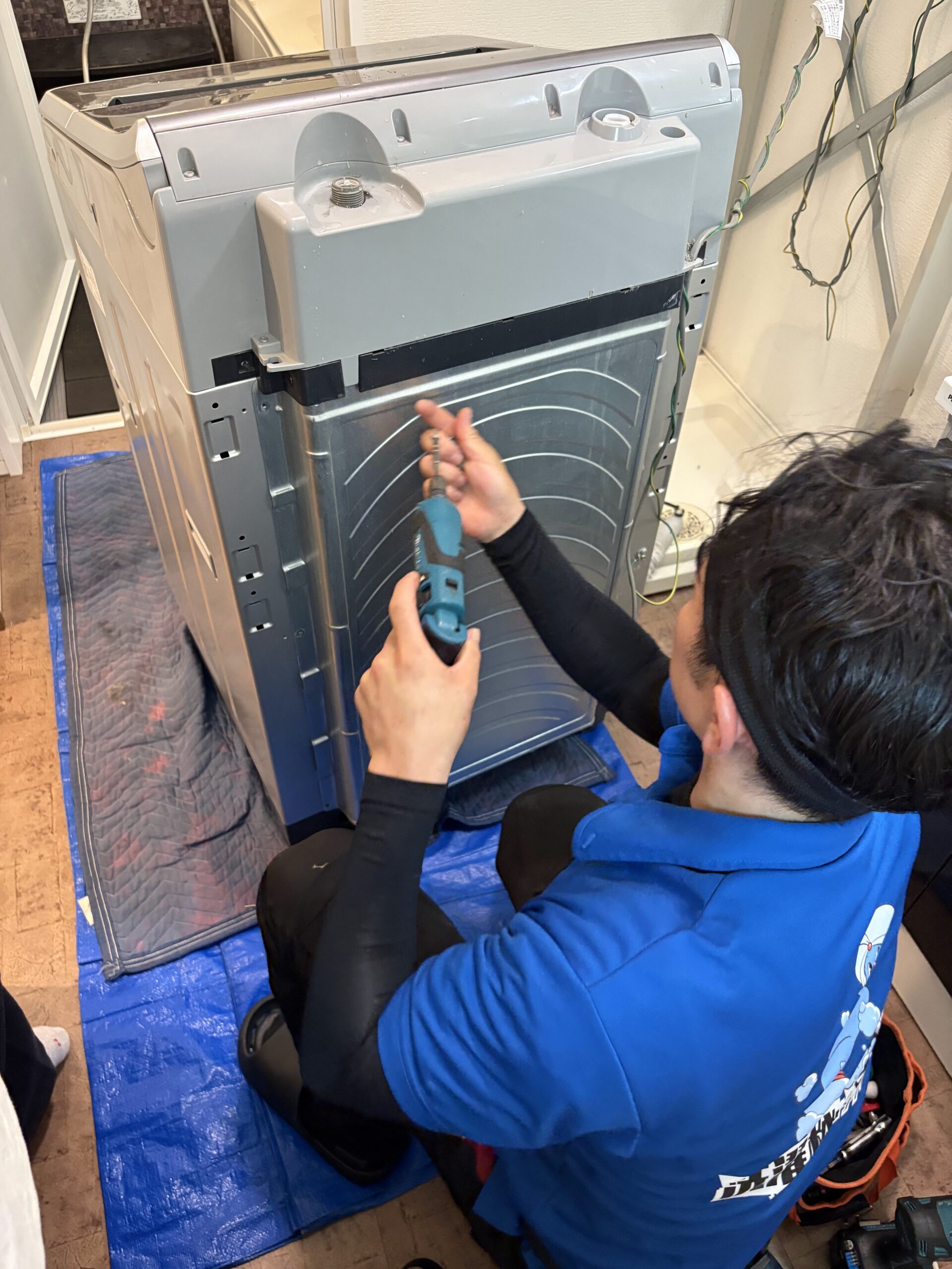 電動ドライバーで洗濯機のカバーを分解する様子